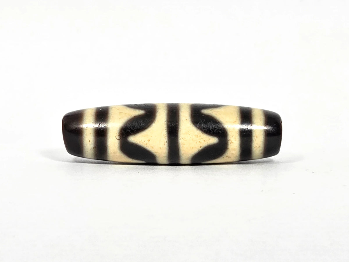 Second lateral profile of antique Tibetan double wave dzi bead showing reverse face with black butterfly wave motif panels and vertical stripe separators on cream agate, 40.4 mm