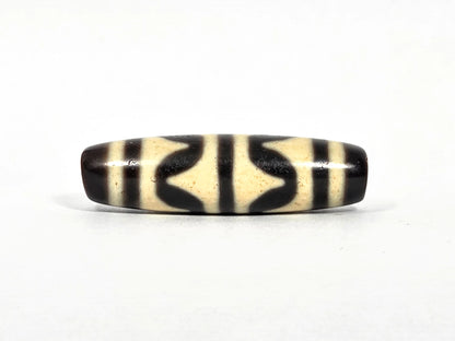 Second lateral profile of antique Tibetan double wave dzi bead showing reverse face with black butterfly wave motif panels and vertical stripe separators on cream agate, 40.4 mm
