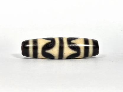 Third lateral profile of antique double wave dzi bead (AT-092826-DW2) showing full motif composition, deep black wave forms on cream-white ground, 40.4 mm × 11.4 mm