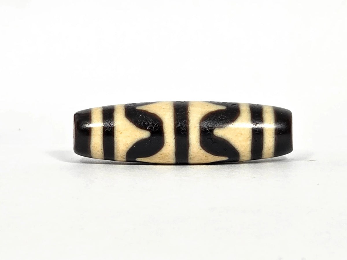 Antique Tibetan double wave dzi bead (AT-092826-DW), first lateral profile showing bold black double wave forms in three panels on cream-white agate ground, 41.1 mm, 200–400 years old