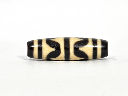 Antique Tibetan double wave dzi bead (AT-092826-DW), first lateral profile showing bold black double wave forms in three panels on cream-white agate ground, 41.1 mm, 200–400 years old