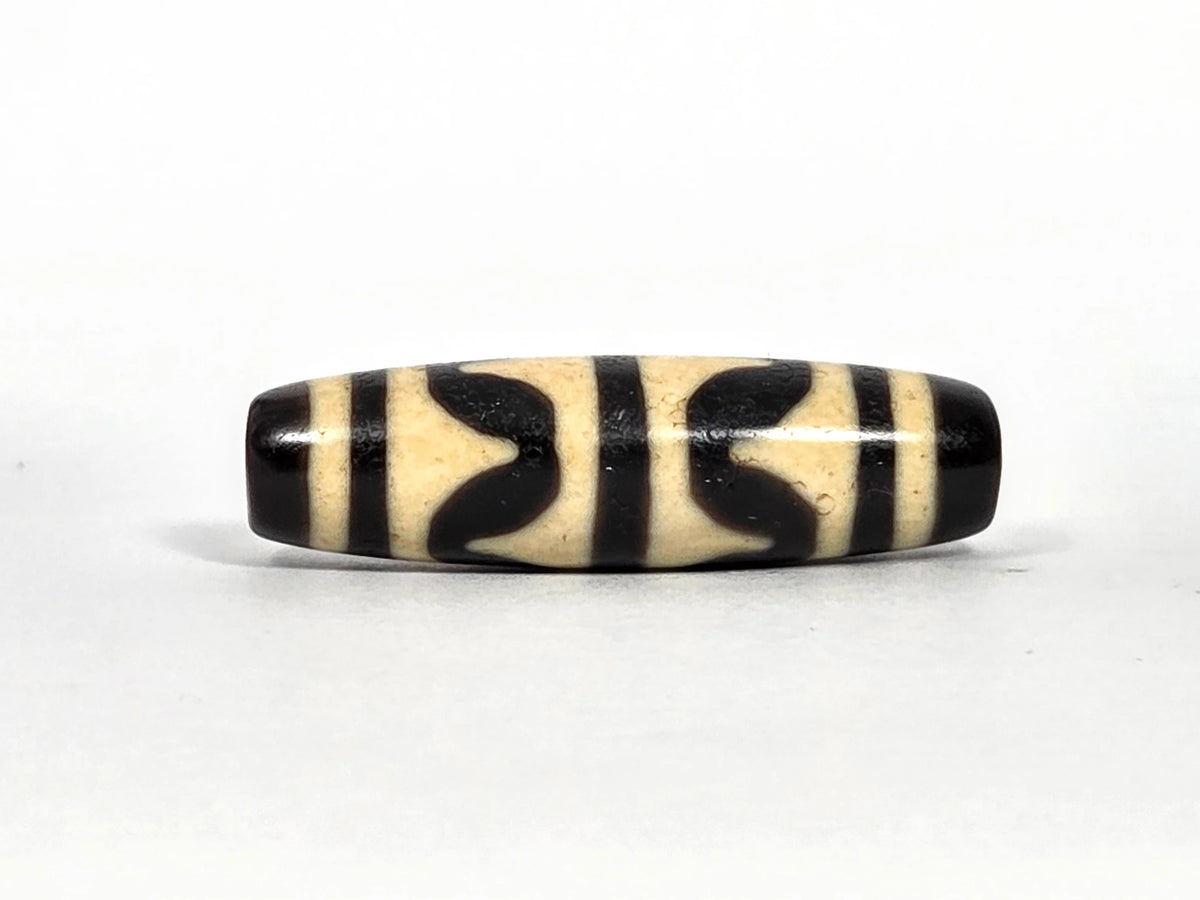 Second lateral profile of antique Tibetan double wave dzi bead showing reverse face with black butterfly wave motif panels and vertical stripe separators on cream agate, 41.1 mm
