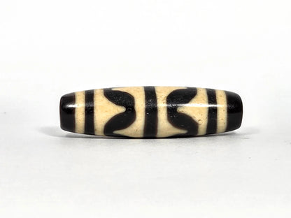 Second lateral profile of antique Tibetan double wave dzi bead showing reverse face with black butterfly wave motif panels and vertical stripe separators on cream agate, 41.1 mm