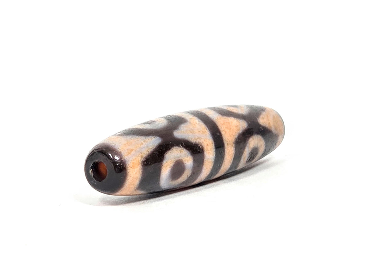 V-061026-6ETTBS angled end, drill hole with warm reddish interior, dark end cap, eye rings wrapping body, unretouched