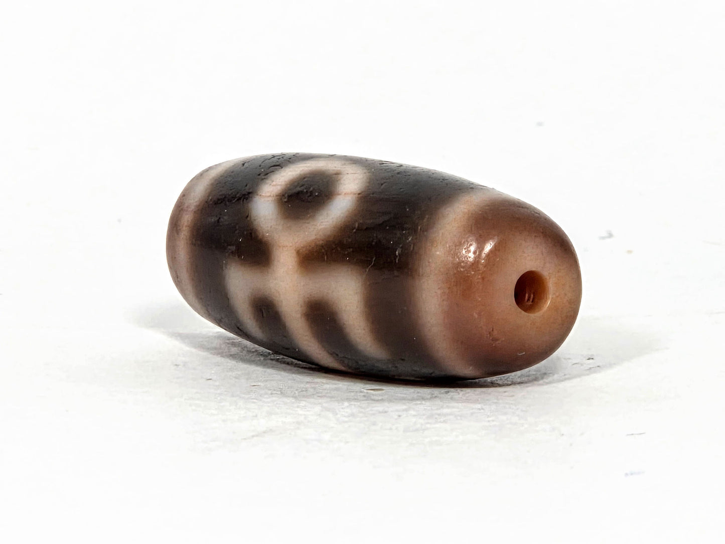 V-071426-BNF end angle A — warm peachy-brown end cap, small clean drill opening, motif visible, unretouched. 