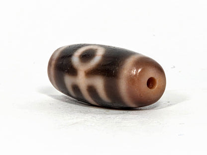 V-071426-BNF end angle A — warm peachy-brown end cap, small clean drill opening, motif visible, unretouched. 