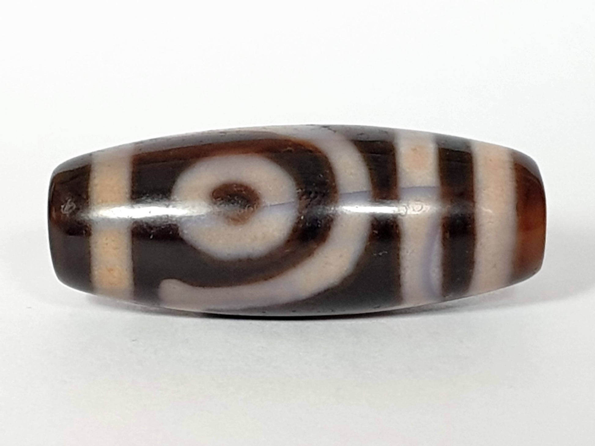 A vintage Dzi bead featuring a captivating Two Eye Motif. This authentic artifact, identified as TD-TwE-1, showcases the intricate craftsmanship and symbolic beauty of ancient Dzi beads.