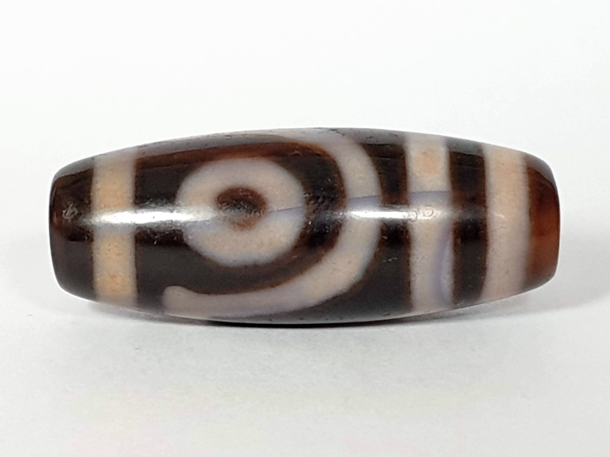 A vintage Dzi bead featuring a captivating Two Eye Motif. This authentic artifact, identified as TD-TwE-1, showcases the intricate craftsmanship and symbolic beauty of ancient Dzi beads.