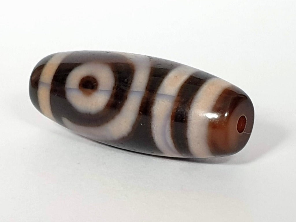 A vintage Dzi bead featuring a captivating Two Eye Motif. This authentic artifact, identified as TD-TwE-1, showcases the intricate craftsmanship and symbolic beauty of ancient Dzi beads.
