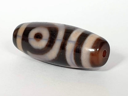 A vintage Dzi bead featuring a captivating Two Eye Motif. This authentic artifact, identified as TD-TwE-1, showcases the intricate craftsmanship and symbolic beauty of ancient Dzi beads.