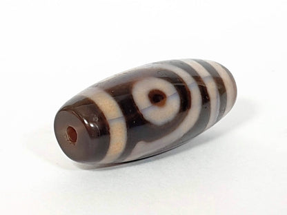 A vintage Dzi bead featuring a captivating Two Eye Motif. This authentic artifact, identified as TD-TwE-1, showcases the intricate craftsmanship and symbolic beauty of ancient Dzi beads.