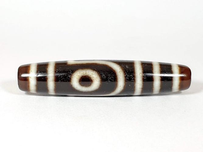 A vintage Dzi bead with a unique Two Eye Motif. This authentic artifact carries historical significance and showcases the captivating design of ancient Dzi beads