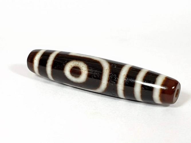 A vintage Dzi bead with a unique Two Eye Motif. This authentic artifact carries historical significance and showcases the captivating design of ancient Dzi beads