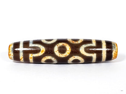 A vintage Dzi bead with a faux antique appearance featuring a captivating seven-eye motif. The bead showcases intricate carvings, with seven eyes symbolizing protection, intuition, and spiritual awakening