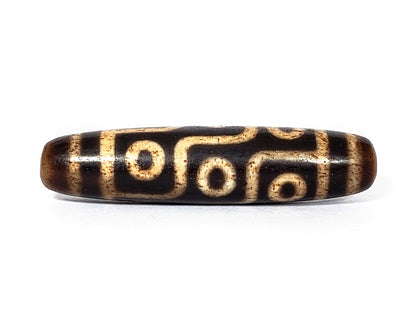A vintage Dzi bead with a faux antique appearance featuring a captivating nine-eye motif. The intricate patterns and worn texture give it an ancient and mystical allure.
