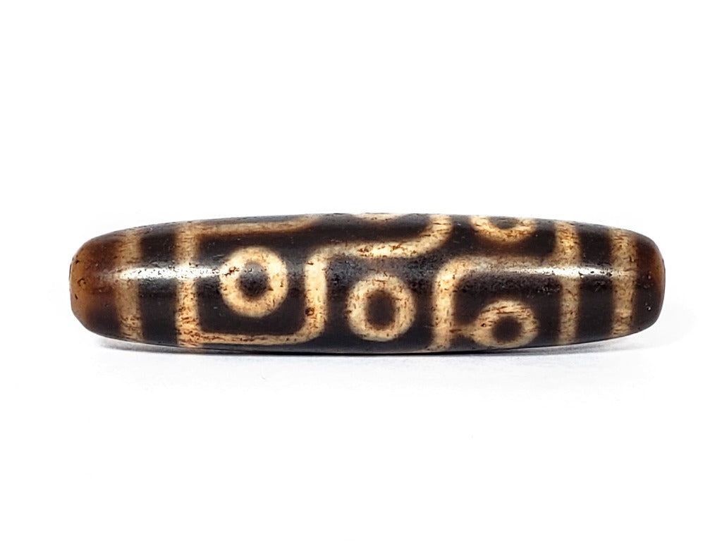 A vintage Dzi bead with a faux antique appearance featuring a captivating nine-eye motif. The intricate patterns and worn texture give it an ancient and mystical allure.