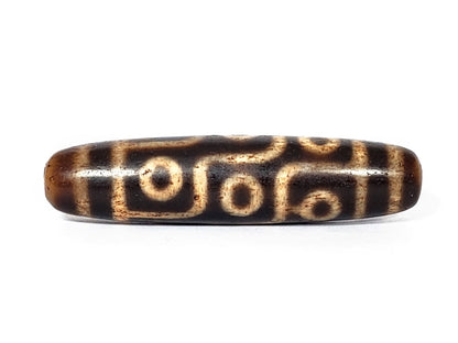 A vintage Dzi bead with a faux antique appearance featuring a captivating nine-eye motif. The intricate patterns and worn texture give it an ancient and mystical allure.