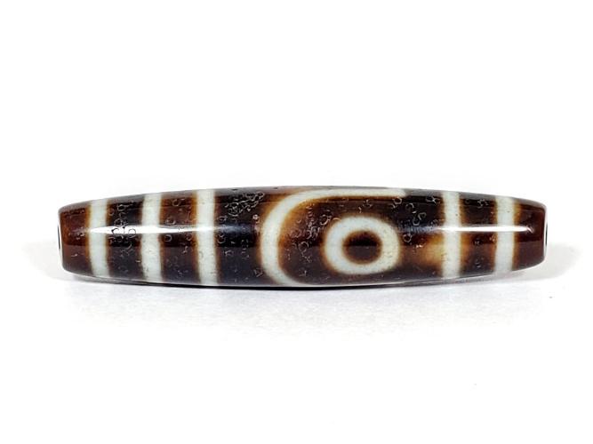 A vintage Dzi bead with a captivating Two Eye Motif. This authentic artifact showcases the timeless beauty and cultural significance of ancient Dzi bead