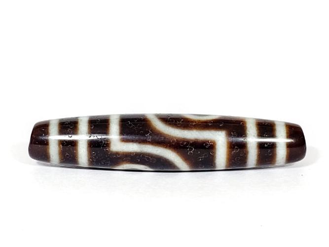 A vintage Dzi bead with a captivating Two Eye Motif. This authentic artifact showcases the timeless beauty and cultural significance of ancient Dzi bead
