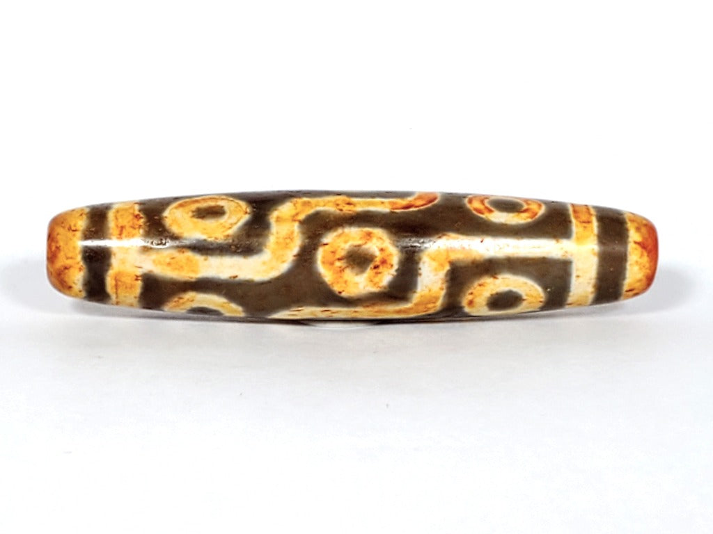 A vintage Dzi bead with a faux antique appearance featuring a mesmerizing nine-eye motif. The bead showcases intricate carvings, with nine eyes symbolizing protection, insight, and spiritual power. 