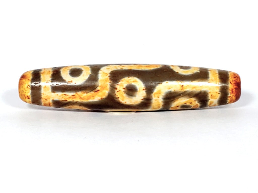 A vintage Dzi bead with a faux antique appearance featuring a mesmerizing nine-eye motif. The bead showcases intricate carvings, with nine eyes symbolizing protection, insight, and spiritual power. 