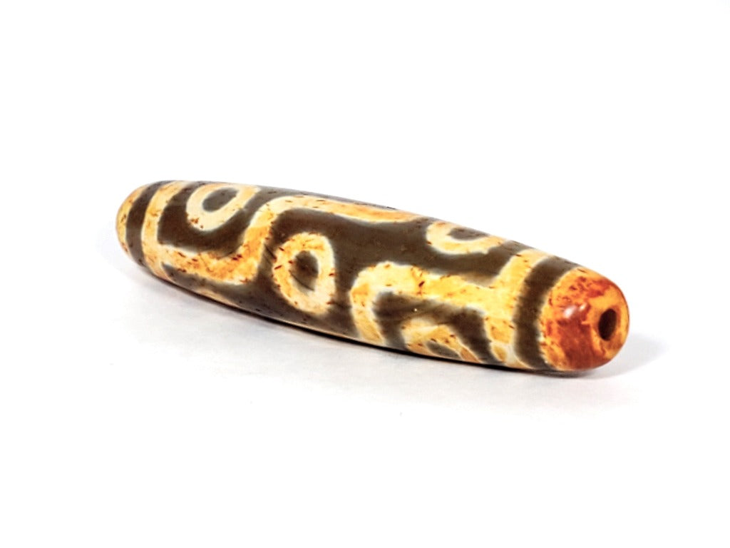 A vintage Dzi bead with a faux antique appearance featuring a mesmerizing nine-eye motif. The bead showcases intricate carvings, with nine eyes symbolizing protection, insight, and spiritual power. 