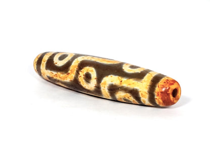 A vintage Dzi bead with a faux antique appearance featuring a mesmerizing nine-eye motif. The bead showcases intricate carvings, with nine eyes symbolizing protection, insight, and spiritual power. 