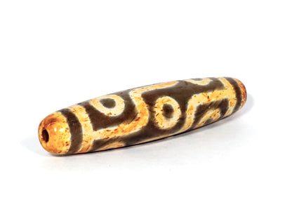 A vintage Dzi bead with a faux antique appearance featuring a mesmerizing nine-eye motif. The bead showcases intricate carvings, with nine eyes symbolizing protection, insight, and spiritual power. 