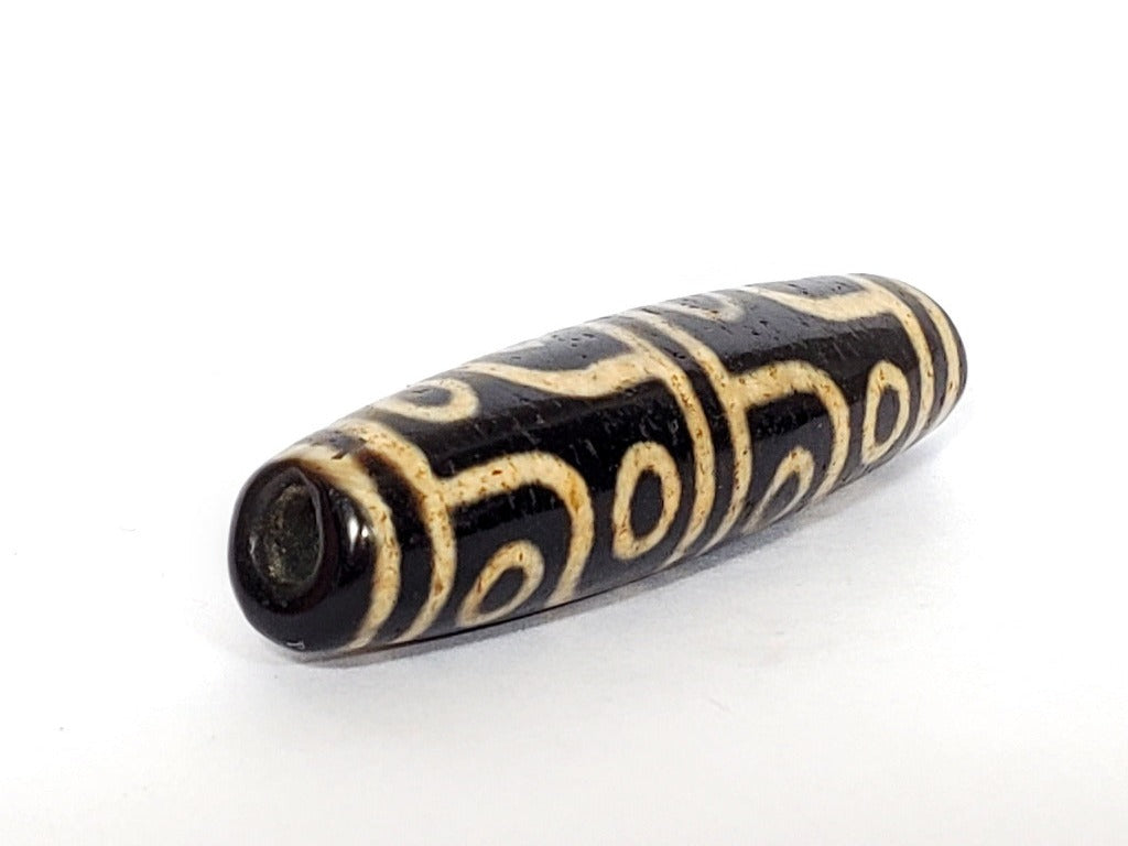 A vintage Dzi bead featuring a captivating Twelve Eye Motif. This authentic artifact embodies the rich history and symbolic significance of ancient Dzi beads