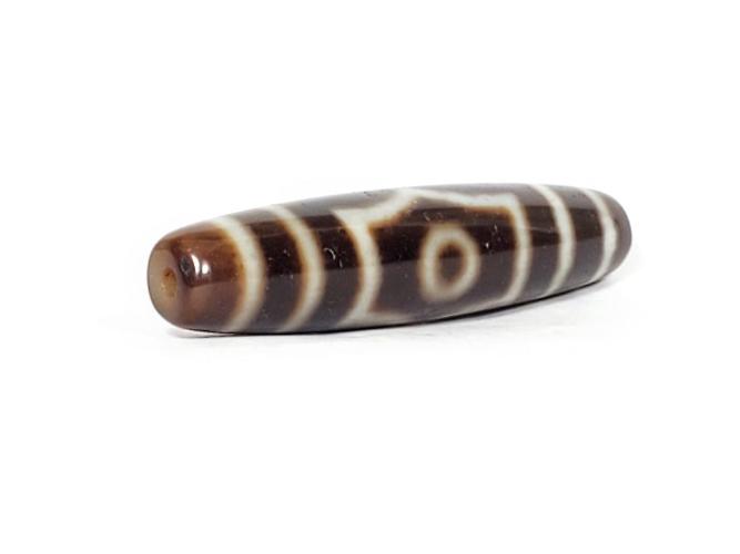 A vintage Dzi bead with a mesmerizing Three Eye Motif. This authentic artifact, identified as TD-ThE-003, showcases the intricate craftsmanship and spiritual symbolism of ancient Dzi beads.