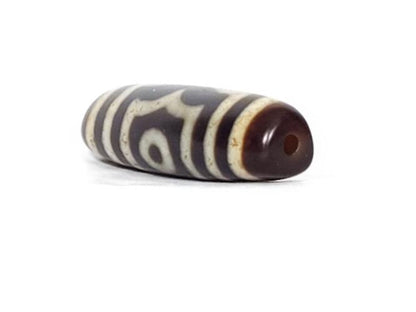 A vintage Dzi bead featuring a rare triangular shape and a captivating Three Eye Motif. This authentic artifact showcases the unique design and spiritual symbolism of ancient Dzi beads
