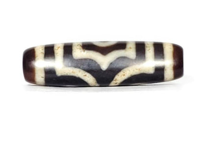 A vintage Dzi bead featuring a rare triangular shape and a captivating Three Eye Motif. This authentic artifact showcases the unique design and spiritual symbolism of ancient Dzi beads